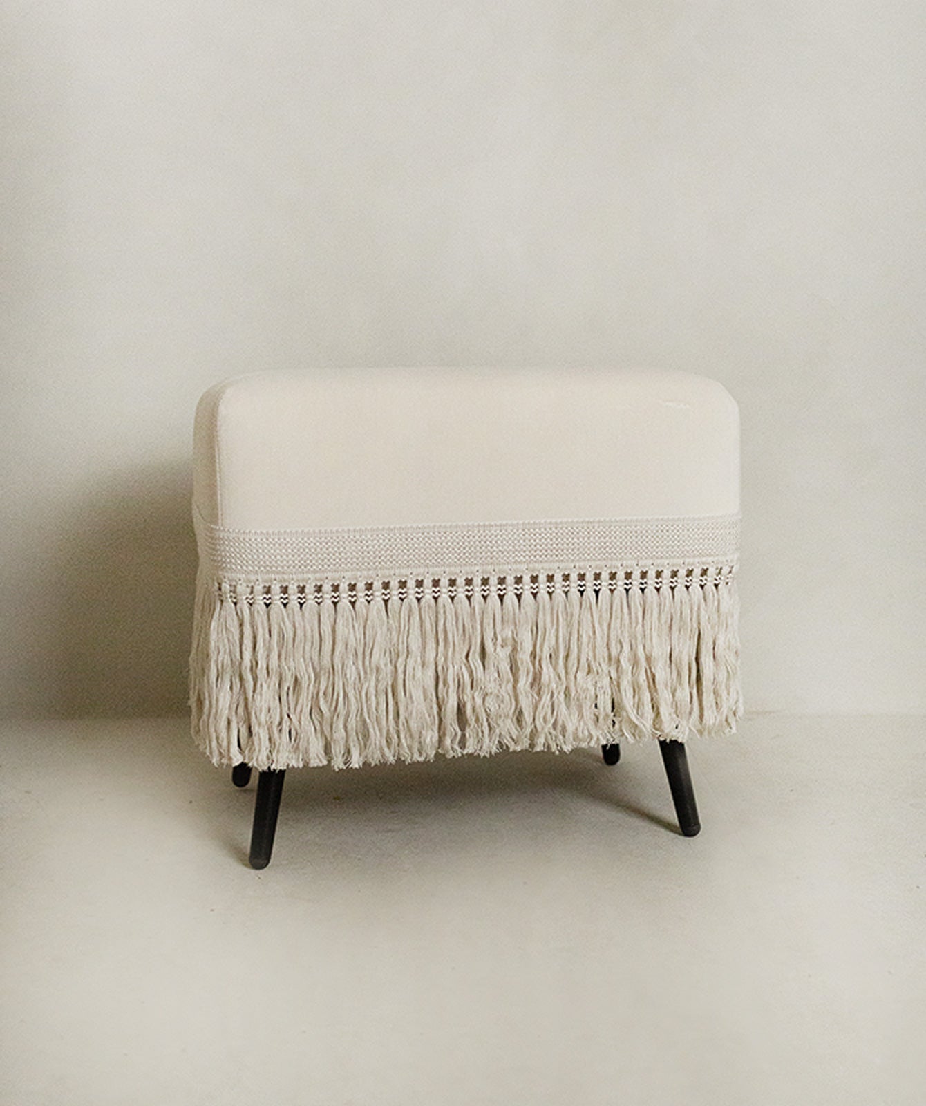 Cream velvet upholstered stool with ecru trim, angled view