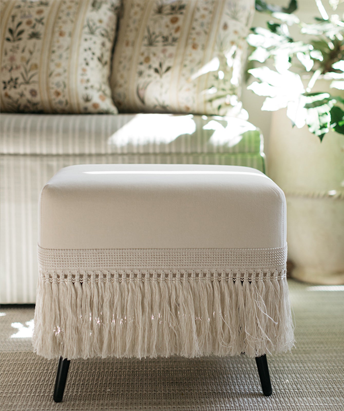 Cream velvet stool in bright sunroom, versatile seating for modern homes