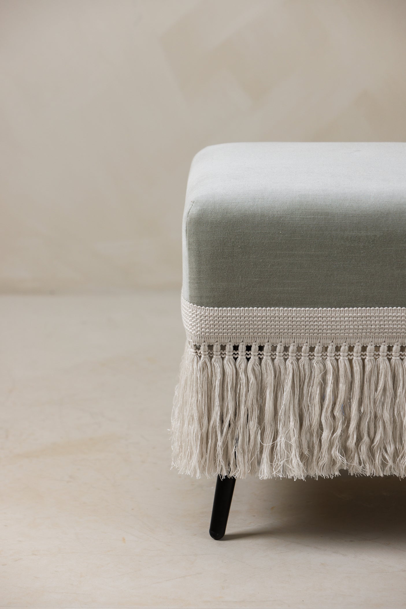 Detail view of Verdigris stool velvet upholstery and handcrafted ecru trim construction