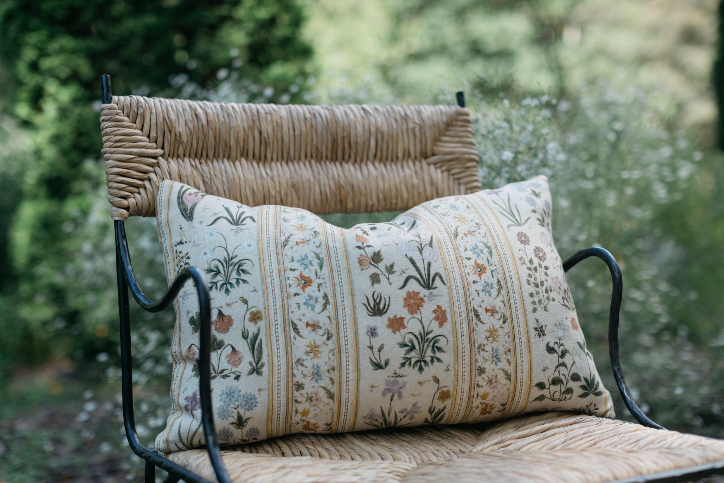Close-up of single Botanico lumbar pillow on chair – garden view – Page House Studio