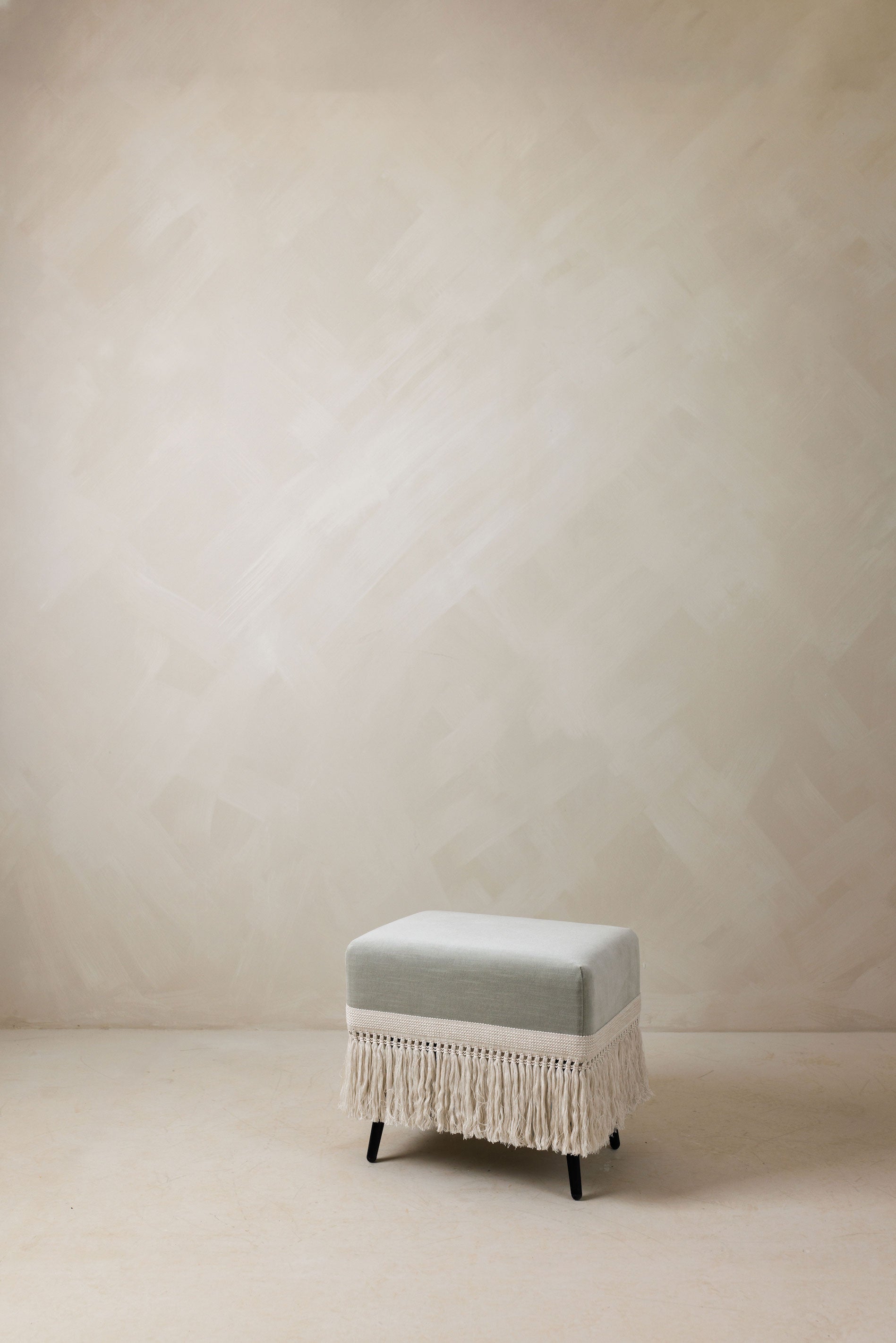 Verdigris stool in bluish-green velvet with fringe trim on black legs for versatile home decor